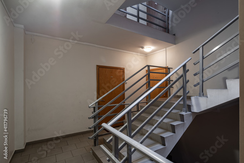 Interior of entrance in modern residential complex. Staircase. Block of flats. Wooden doors.