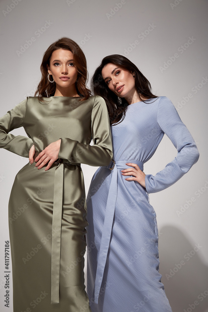 Foto Stock Two sexy brunette woman luxury lifestyle bright makeup wear  natural organic silk midi dress and high heels perfect body fashion model  style for meeting party romantic date studio grey background.