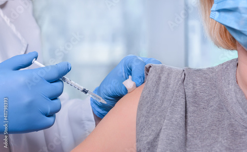 The doctor gives a vaccine to the patient s shoulder at the clinic. The concept of vaccination  immunity during the outbreak of the coronavirus pandemic