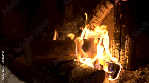 The wood burning inside a fireplace at a rural house. The flame and fire consume the wood of the logs little by little