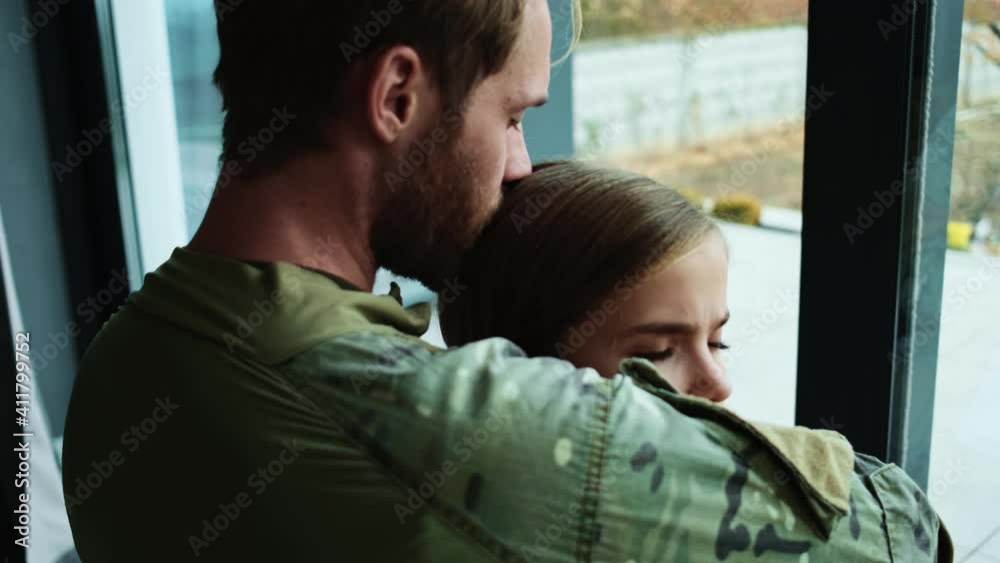 A close-up view of a sad soldier man is hugging his crying young daughter sitting at home before leaving A close-up view of a sad soldier man is hugging his crying young daughter sitting at home before leaving
