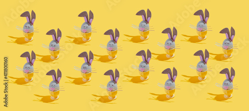 a lot of Easter eggs made as Easter bunnies with various emotions on a yellow background
