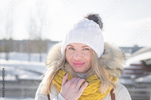 Beautiful blonde girl in white clothes in winter on a city