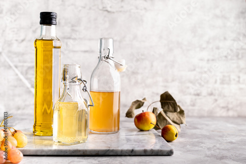 Original glass bottles with different vinegar on a marble table against a background of a white brick wall. Copy space.