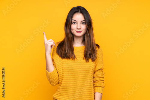 Young caucasian woman isolated on yellow background pointing with the index finger a great idea