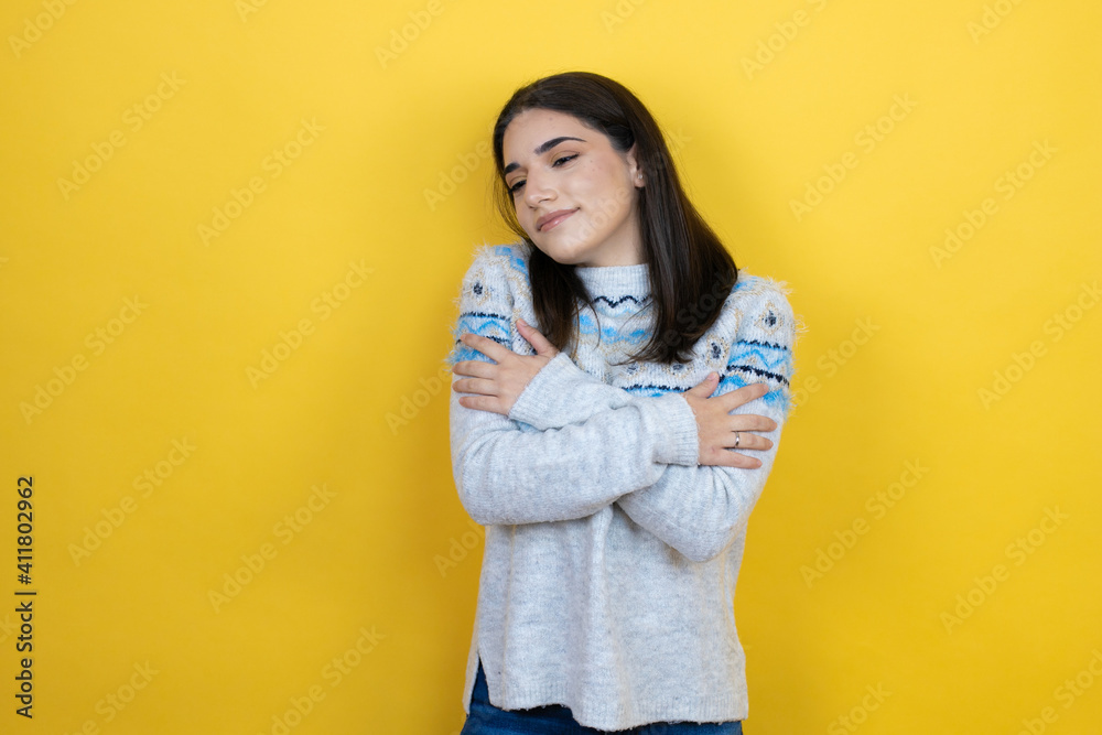 Young caucasian woman wearing casual sweater over yellow background hugging oneself happy and positive, smiling confident Young caucasian woman wearing casual sweater over yellow background hugging oneself happy and positive, smiling confident