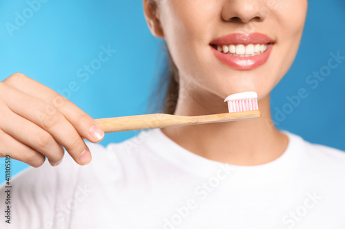 Woman holding toothbrush with paste on blue background  closeup