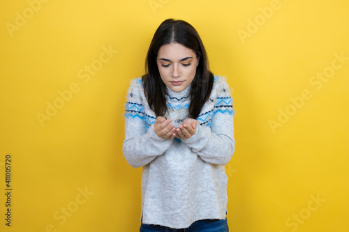 Young caucasian woman wearing casual sweater over yellow background Smiling with hands palms together receiving or giving gesture. Hold and protection