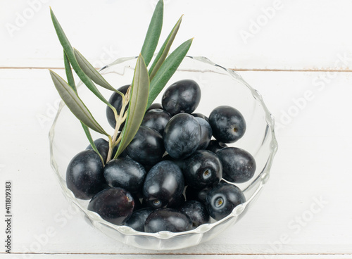 Olive branch with olives served in bowl on white background