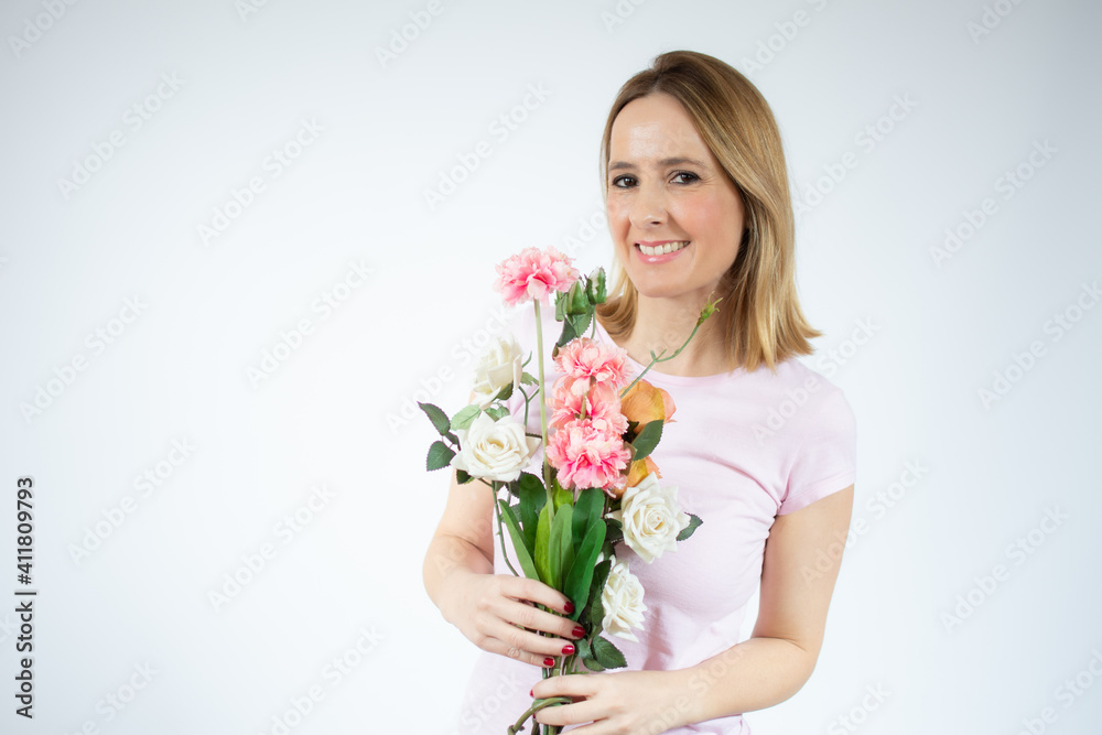 Portrait of a beautiful young woman in casual t-shirt holding big bouquet of flowers isolated over white background