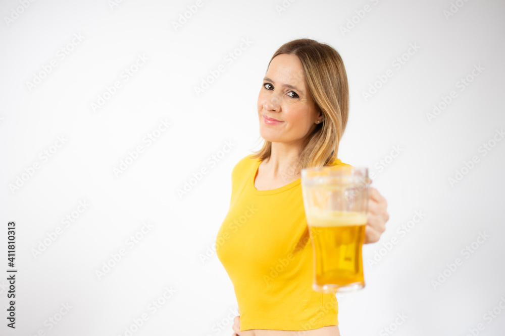 Cheerful young woman holding a beer mug full of beer and smiling over white background Cheerful young woman holding a beer mug full of beer and smiling over white background