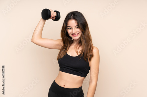 Young sport woman making weightlifting isolated on beige background © luismolinero