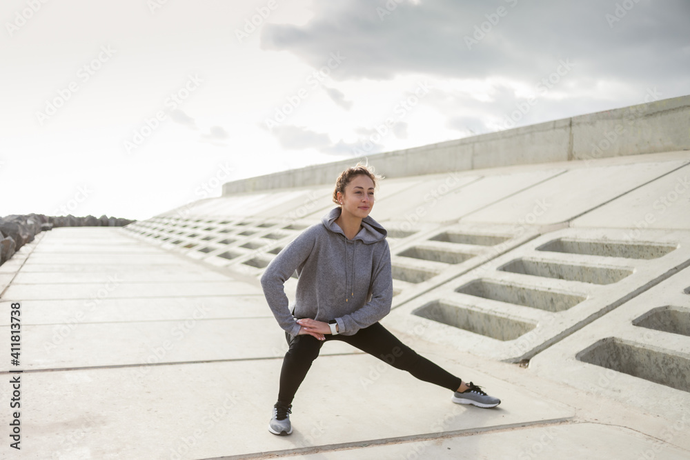 Attractive sporty woman in sportswear trains outdoors. Warm up or stretching, healthy lifestyle. Attractive sporty woman in sportswear trains outdoors. Warm up or stretching, healthy lifestyle.