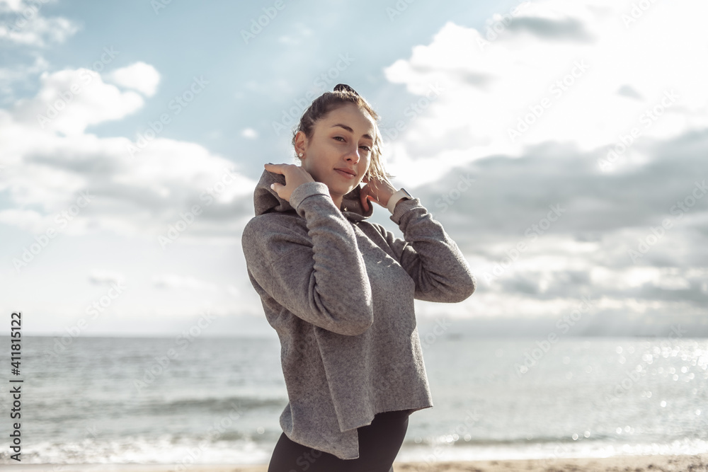 Portrait of an attractive fit slim woman in sportswear on the beach at bright sunny day Portrait of an attractive fit slim woman in sportswear on the beach at bright sunny day