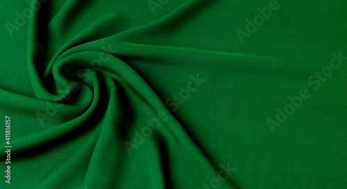 Green background with a texture of natural cotton fabric laid in waves with a place for text. The concept of design in the interior, the selection of draperies and textiles.