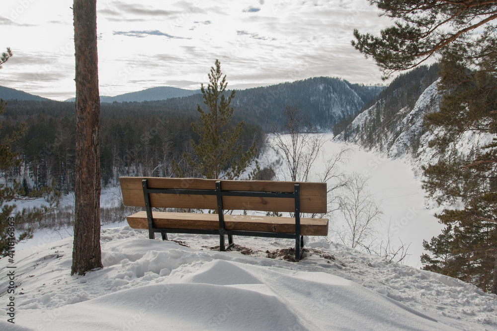Lonely bench on the side of a mountain. Winter landscape.