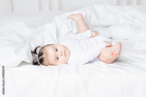 baby lying on the bed at home with his feet up, the concept of a happy loving family and children