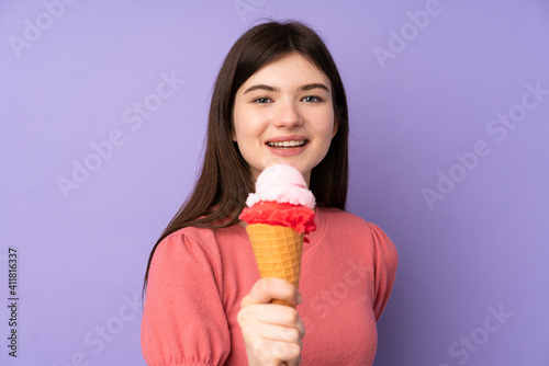 Young Ukrainian teenager girl holding a cornet ice cream over isolated purple background