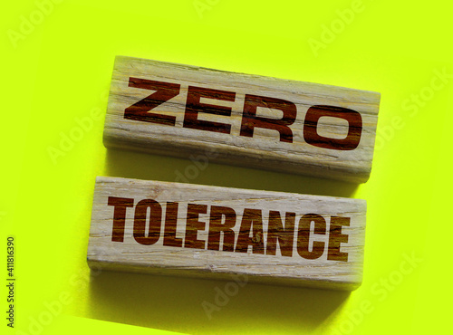 Zero tolerance - words from wooden blocks with letters, severely punishing all unacceptable behaviour, zero tolerance concept, yellow background photo