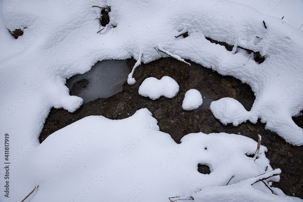 water emerges from beneath the snow, cold and clear water emerges from beneath the snow, cold and clear