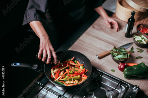 unrecognizable chef pouring oil into frying pan