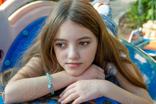 Beautiful emotional teenager girl lying on the children's city playground on a sunny day