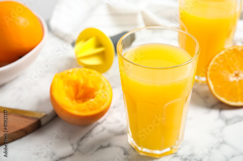 Fresh ripe orange, juice and reamer on white marble table, closeup. Space for text