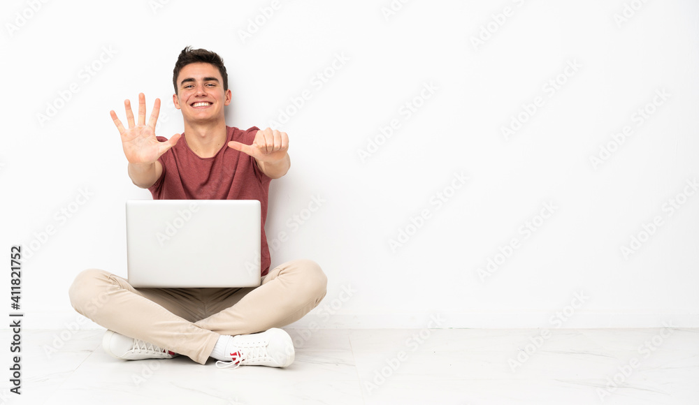 Teenager man sitting on the flor with his laptop counting six with fingers Teenager man sitting on the flor with his laptop counting six with fingers