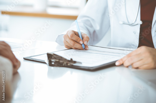Unknown woman-doctor consulting patient and using clipboard with a medication history record. Medicine concept