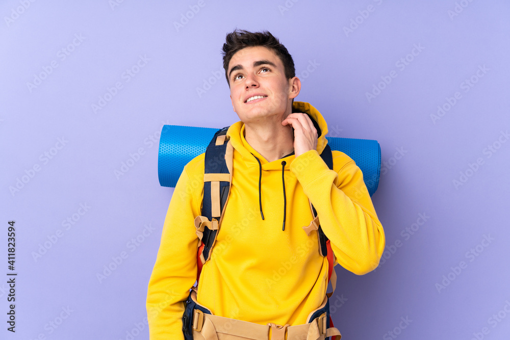 Teenager caucasian mountaineer man with a big backpack isolated on purple background thinking an idea
