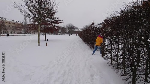 Woman in a yellow jacket walks through the Lene Voigt Park in Leipzig in winter photo