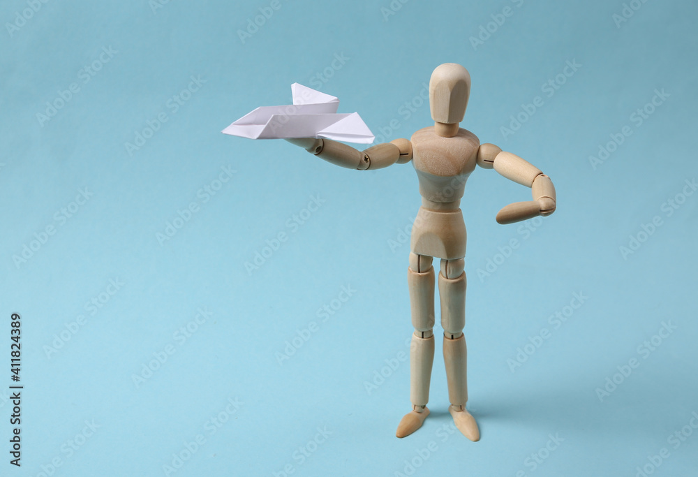 Wooden puppet with paper airplane on blue background Wooden puppet with paper airplane on blue background