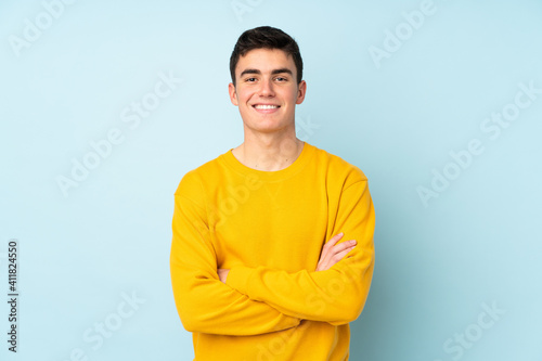 Teenager caucasian handsome man isolated on purple background keeping the arms crossed in frontal position