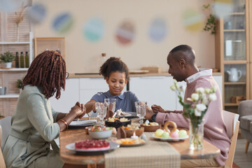 Portrait of modern African -American family enjoying dinner together while celebrating easter at home, focus on smiling teenage girl in center, copy space