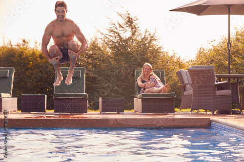 Father Jumps Into Outdoor Pool On Summer Vacation Watched By Mother And Son photo