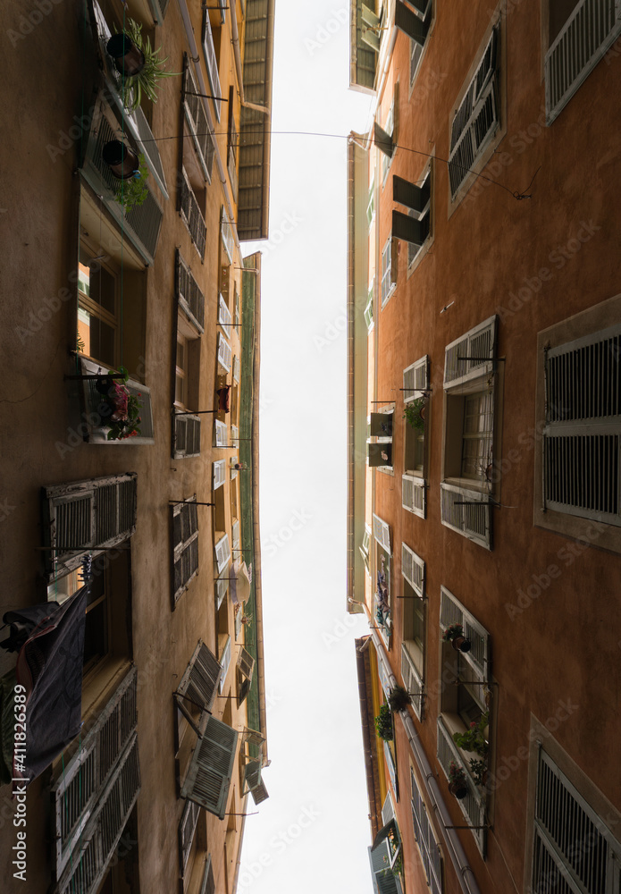 Very narrow street, photographed from below so that the sky between two buildings can be appreciated.