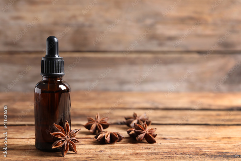 Bottle of essential oil and anise on wooden table. Space for text Bottle of essential oil and anise on wooden table. Space for text