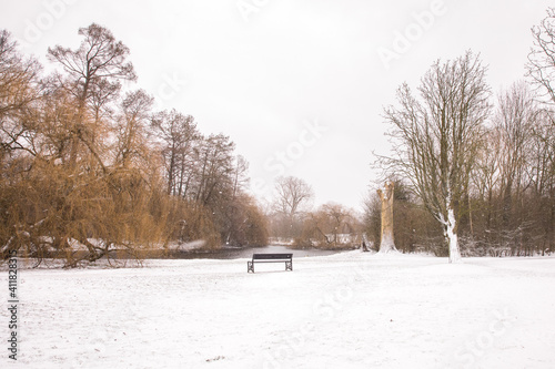 winter view of snowy white Vondelpark  in Amsterdam with a bench under snow