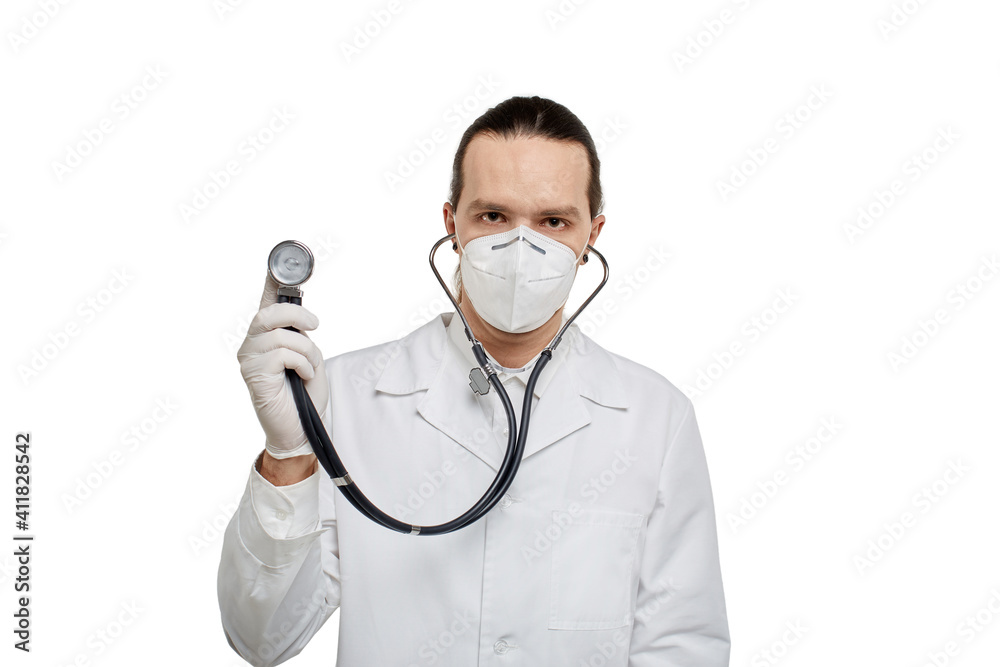 A doctor in a medical gown and mask holds a phonendoscope in his hand. The concept of a heartbeat. White isolated background. A doctor in a medical gown and mask holds a phonendoscope in his hand. The concept of a heartbeat. White isolated background.