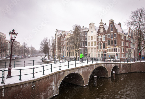 Winter snow view of Dutch canal and old houses in the historic city of Amsterdam, the Netherlands