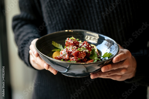 Man holding a bowl of marinated chicken in spicy sauce with daikon 