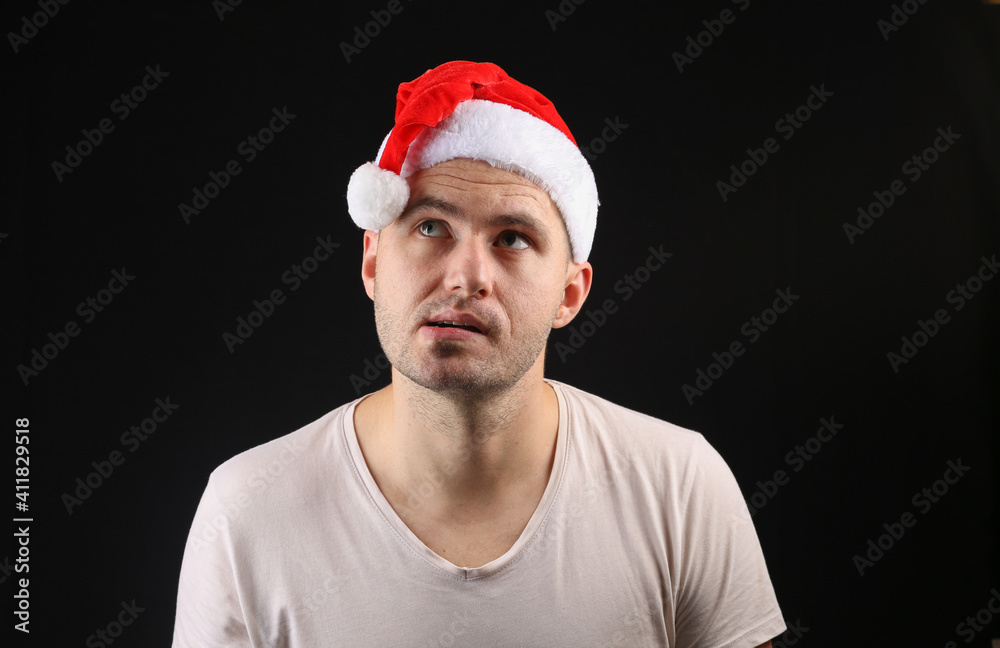 Funny man in a santa hat on a black background. Funny man in a santa hat on a black background.