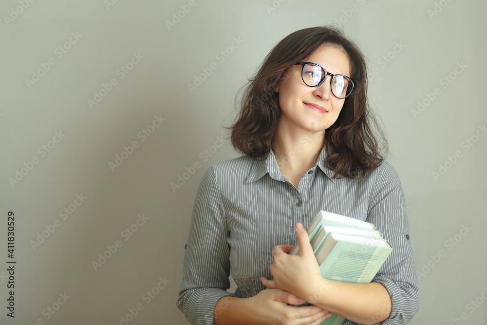 Lovely curly brunette girl with a stack of books on gray background isolated Lovely curly brunette girl with a stack of books on gray background isolated