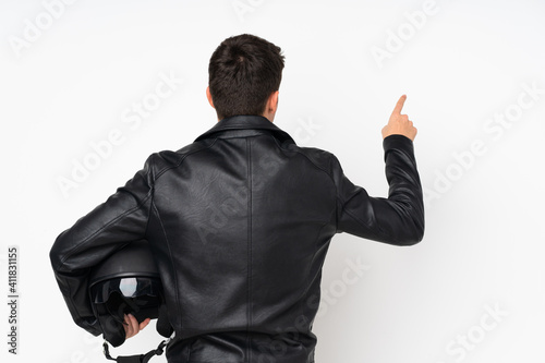 Man holding a motorcycle helmet isolated on white background pointing back with the index finger photo