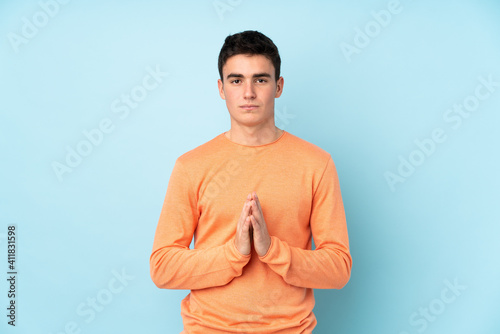 Teenager caucasian handsome man isolated on purple background pleading