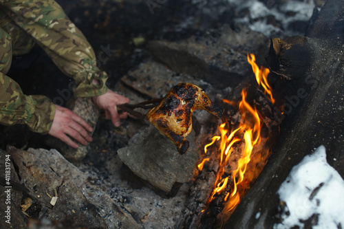 Traveller roasts a piece of meat on an bonfire, close-up.