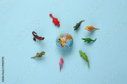 Fototapeta Naklejka Na Ścianę i Meble -  Toy dinosaurs and planet earth on blue background