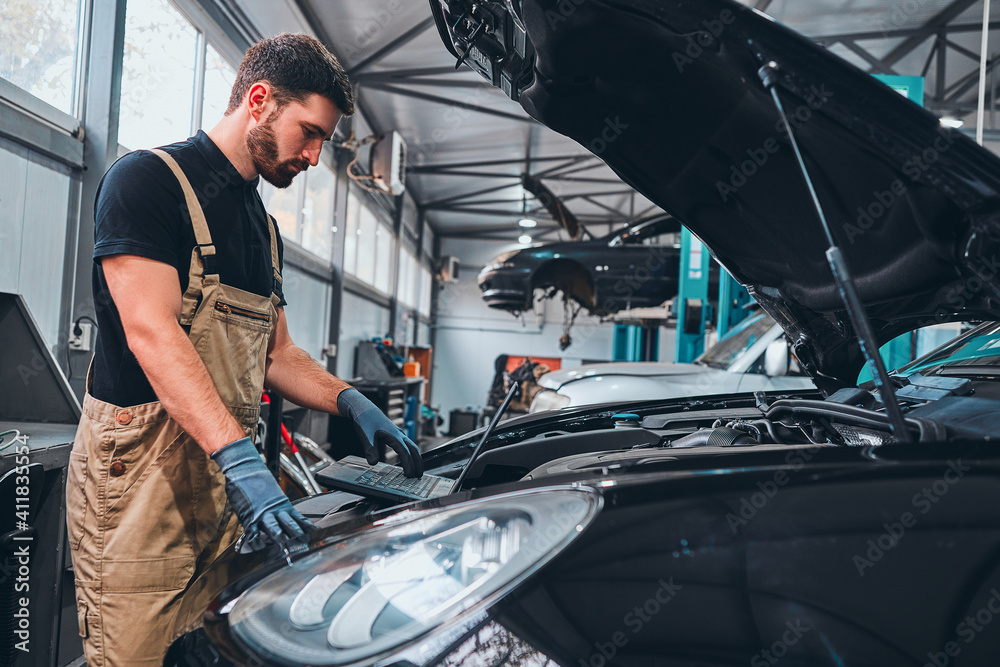 Professional car mechanic with laptop working in auto repair service. Professional car mechanic with laptop working in auto repair service.