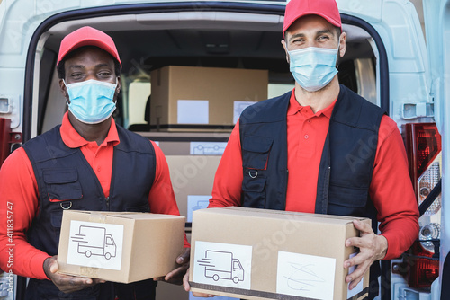 Multiracial workers delivering boxes while wearing safety masks during coronavirus outbreak - Focus on faces