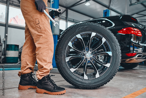 Mechanic holding a tire at the repair garage. Replacement of winter and summer tires. photo
